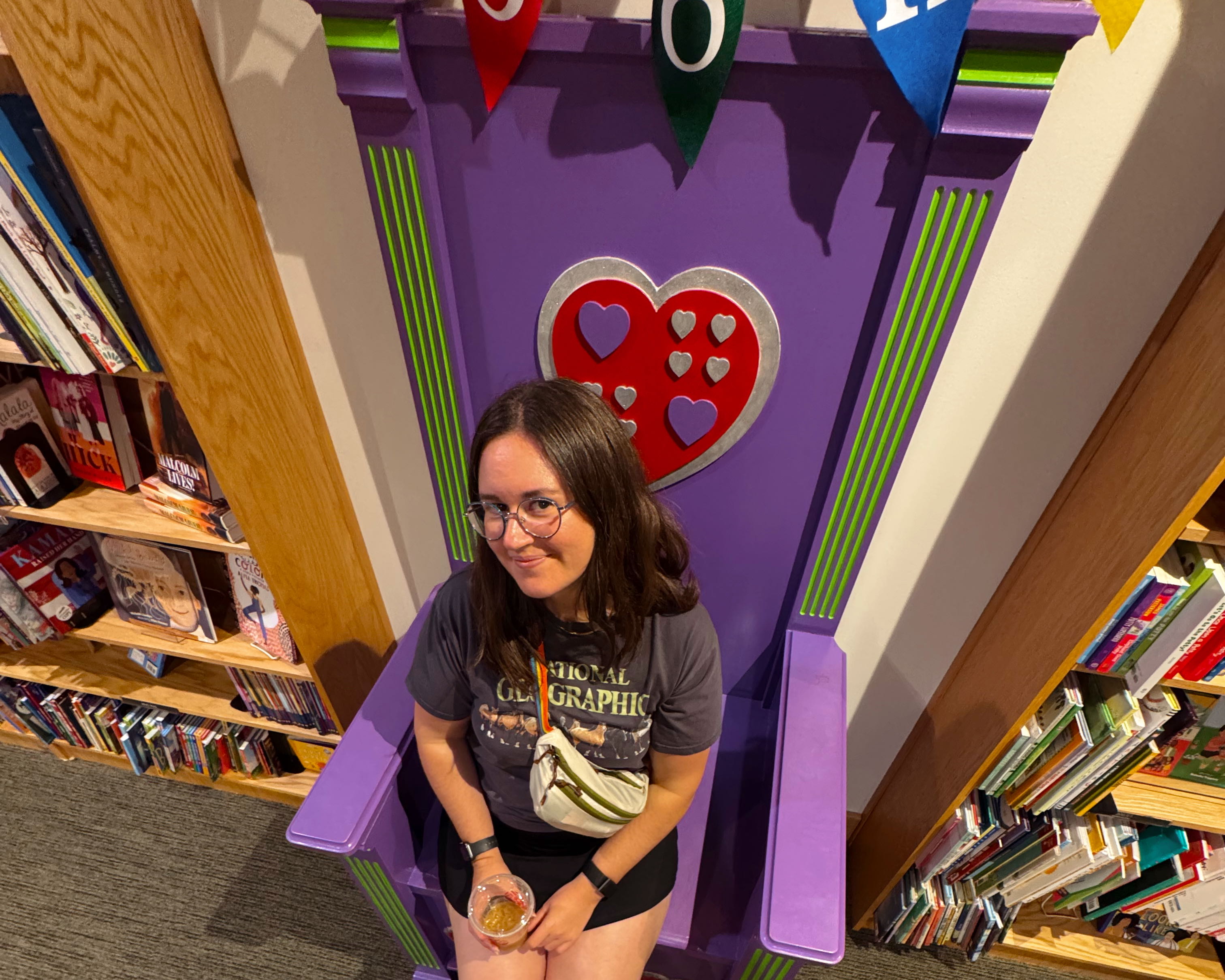Photo with a 0.5 lens and a slight fisheye effect of Bella sitting on a large purple chair in a bookstore.