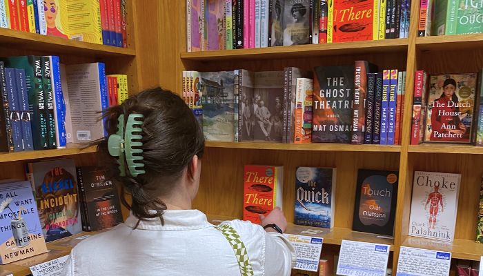 Photo of the back of Bella's head and shoulders in front of a shelf of books in a bookstore.